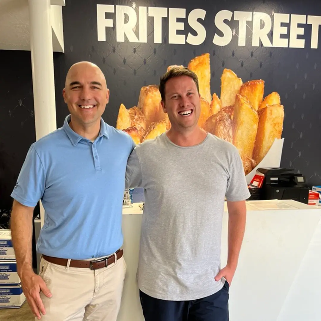 Owner of Frites Street with Josh standing in front of the business sign