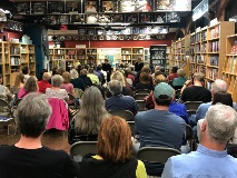 Room full of people listening to a book reading at the Poisoned Pen.